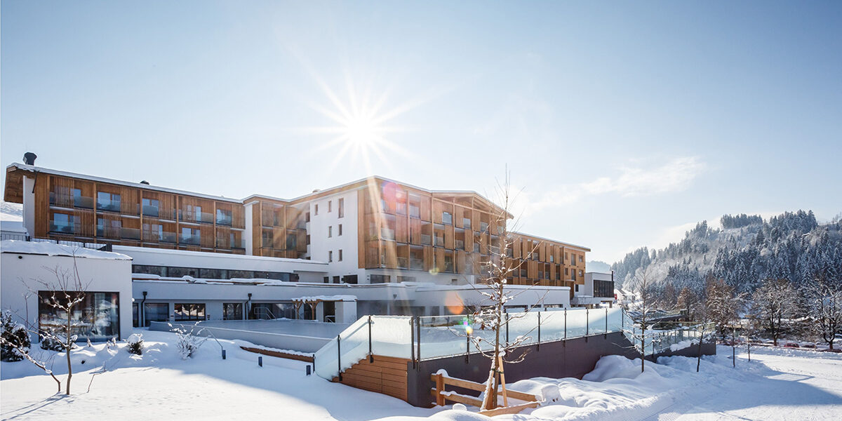 Moderne Hotelanlage Das Hohe Salve im verschneiten Winter bei strahlendem Sonnenschein und blauem Himmel.