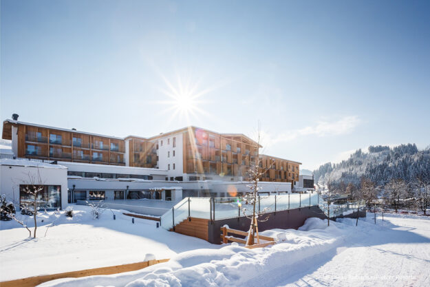 Das Hohe Salve Blog Moderne Hotelanlage Das Hohe Salve im verschneiten Winter bei strahlendem Sonnenschein und blauem Himmel.