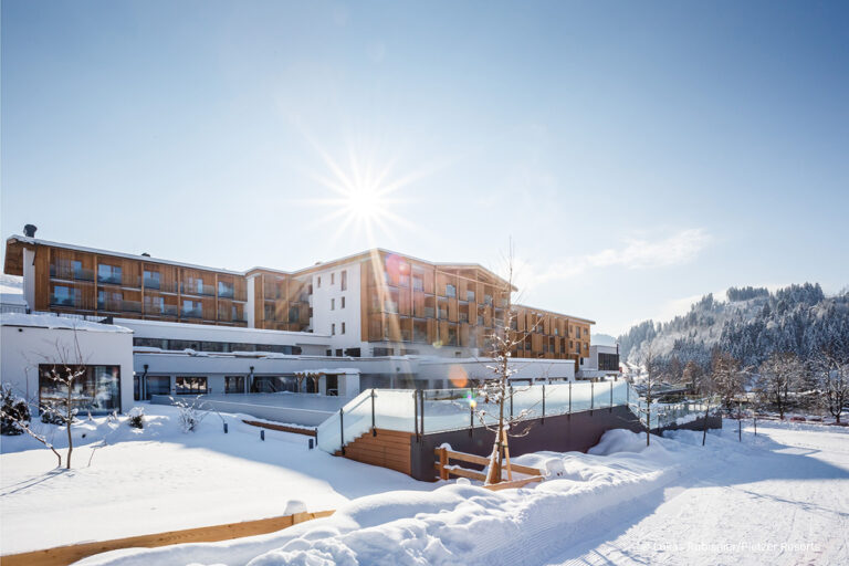 Moderne Hotelanlage Das Hohe Salve im verschneiten Winter bei strahlendem Sonnenschein und blauem Himmel.