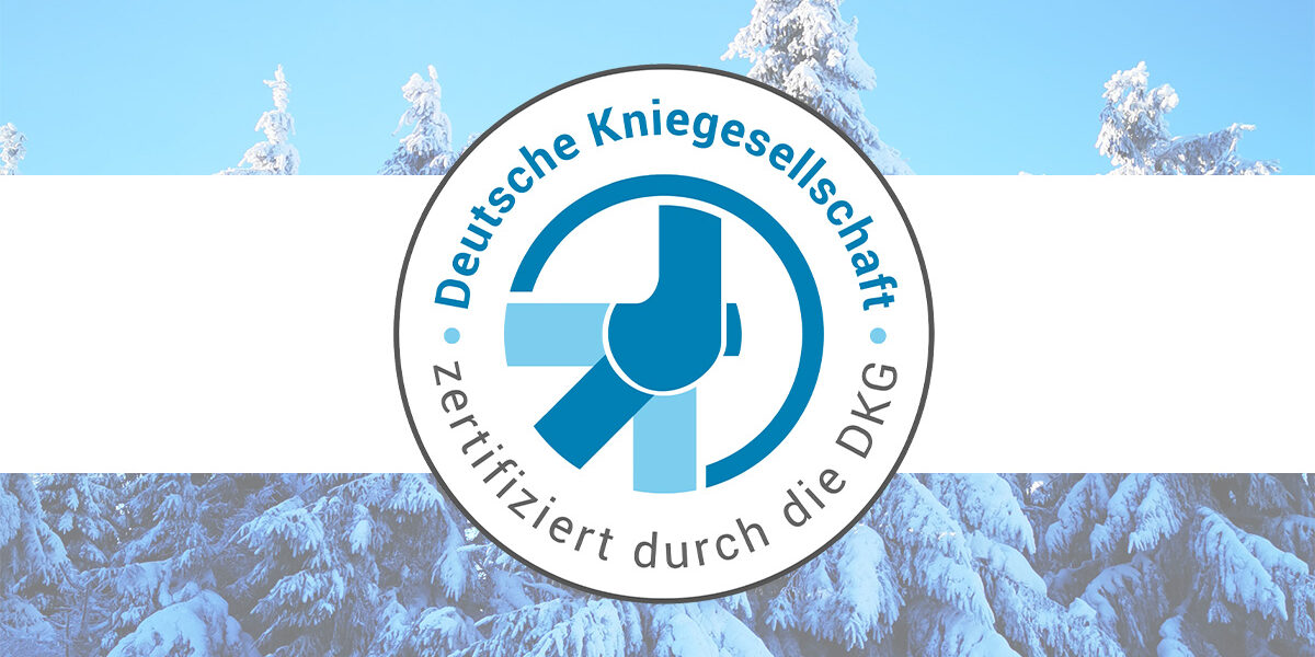 Patronat DKG Blog Zertifizierungssiegel der Deutschen Kniegesellschaft (DKG) auf weißem Banner vor verschneiter Nadelwald-Landschaft.