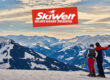 Zwei Skifahrer blicken von einer verschneiten Piste auf ein verschneites Bergpanorama der SkiWelt Wilder Kaiser - Brixental.