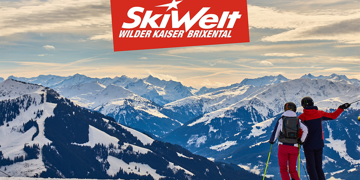WilderKaiserBlog Zwei Skifahrer blicken von einer verschneiten Piste auf ein verschneites Bergpanorama der SkiWelt Wilder Kaiser - Brixental.